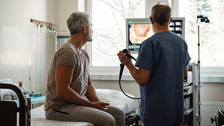 A doctor and patient in an exam room look at a screen with an image of the patient