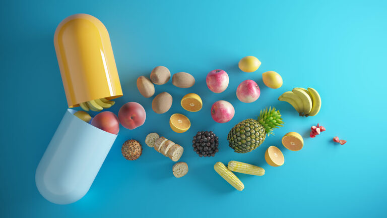 What are vitamins? an illustration showing fruits, vegetables and other foods falling out of an open pill capsule meant to represent a vitamin supplement