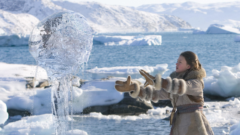 Here’s how to levitate something without magic a girl in a parka, gloves and boots stands on a sheet of ice and snow with her hands out in front of her to levitate a ball of seawater into the air